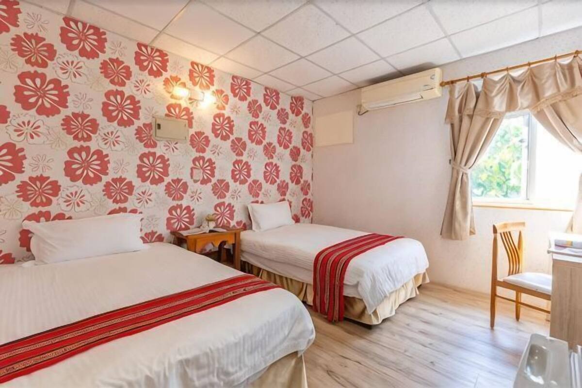 A room with two beds, a desk, and a chair.