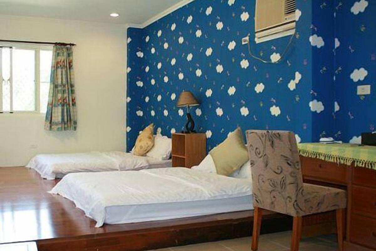 A room with two beds, a desk, and a chair.
