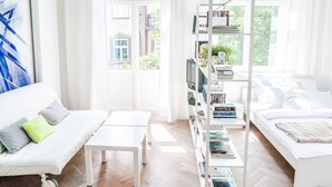 A bright, modern living room with a white sofa, a coffee table, and a bookshelf filled with books. - Boom Apartments (Kraków)