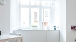 A bright, white room with a large window, a white table, and a chair. - Boom Apartments (Kraków)
