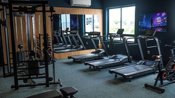 A gym with treadmills, weight machines, and a mirrored wall.