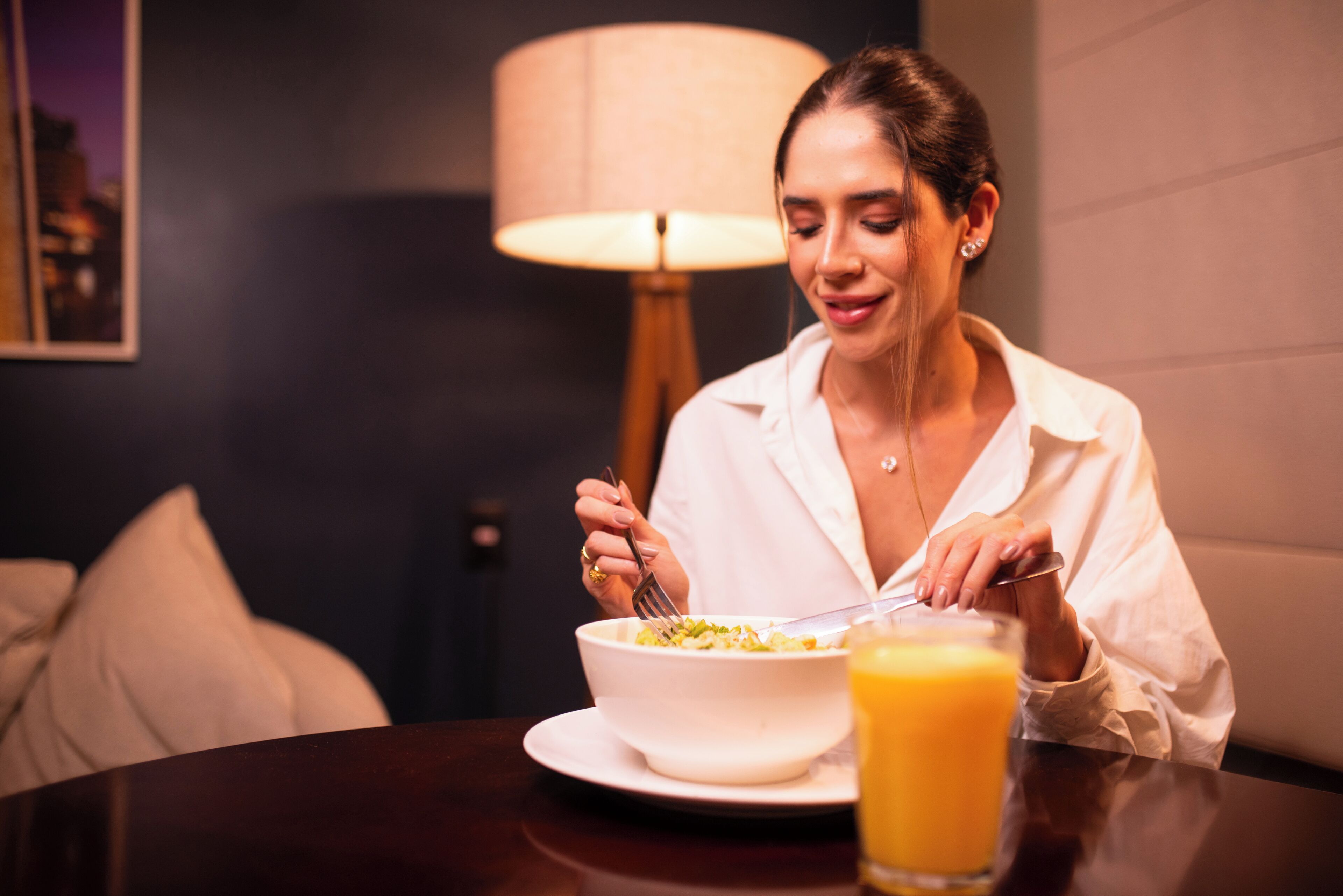 Uma pessoa à mesa, com um prato de comida e um copo de suco de laranja.