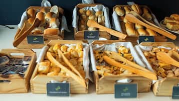 Diversos productos alimenticios expuestos en cajas de madera con etiquetas, como pan, pasteles y otras preparaciones horneadas.