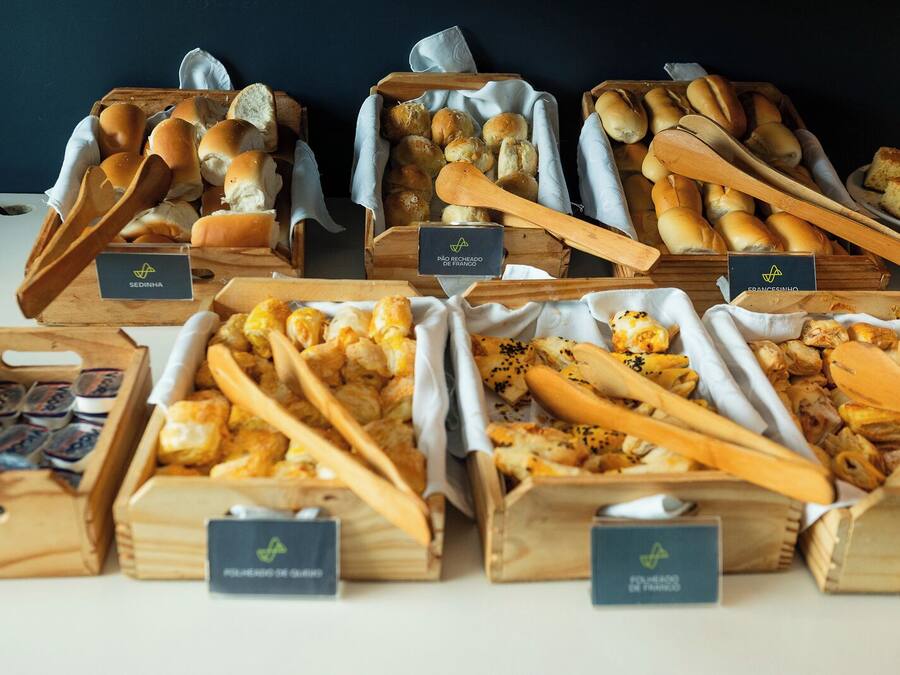A variety of food items displayed in wooden boxes with labels, including bread, pastries, and other baked goods.