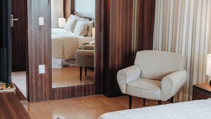 A hotel room with a bed, a chair, a desk, a mirror, and a window with curtains. - Hotel Serrano (Campina Grande)