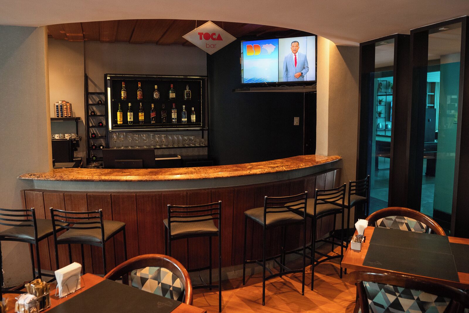A bar area with a TV screen, bar counter, and seating.