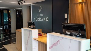 A hotel reception desk with a marble design, a digital screen, and a telephone. - Hotel Serrano (Campina Grande)