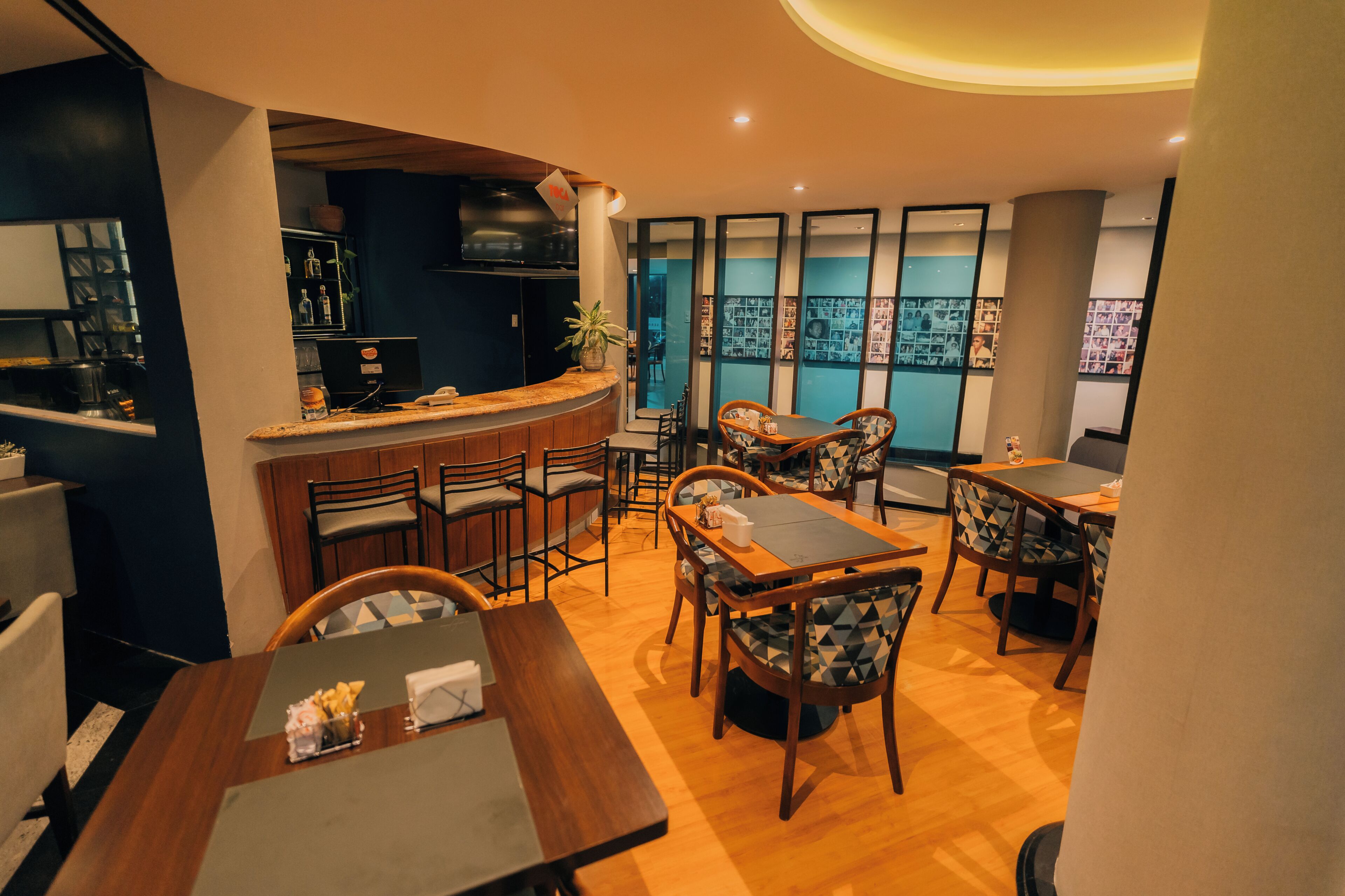 Un restaurante con barra, varias mesas para comer y sillas.