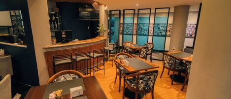 Un restaurante con barra, varias mesas para comer y sillas.