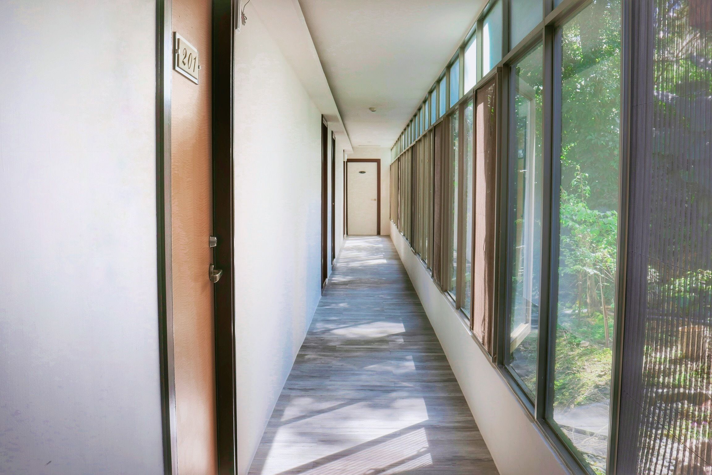 A corridor with large windows on one side and a door on the other.