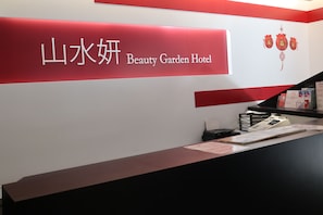 A reception desk at the Beauty Garden Hotel with a red and white color scheme and Chinese characters.