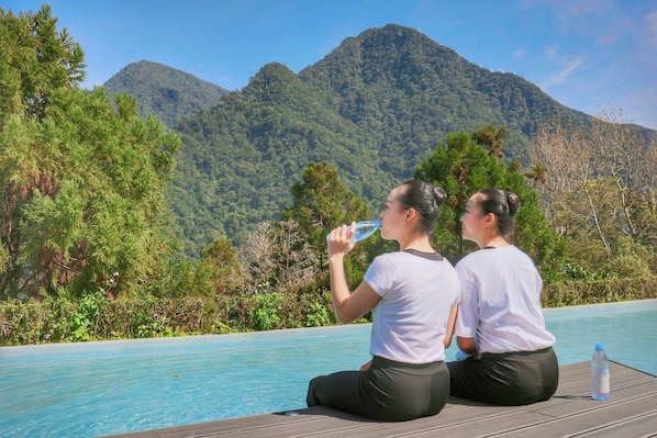 Two people sitting by a pool with a mountain view.