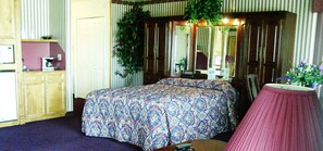 A bedroom with a large bed, a dresser, a mirror, and a potted plant.