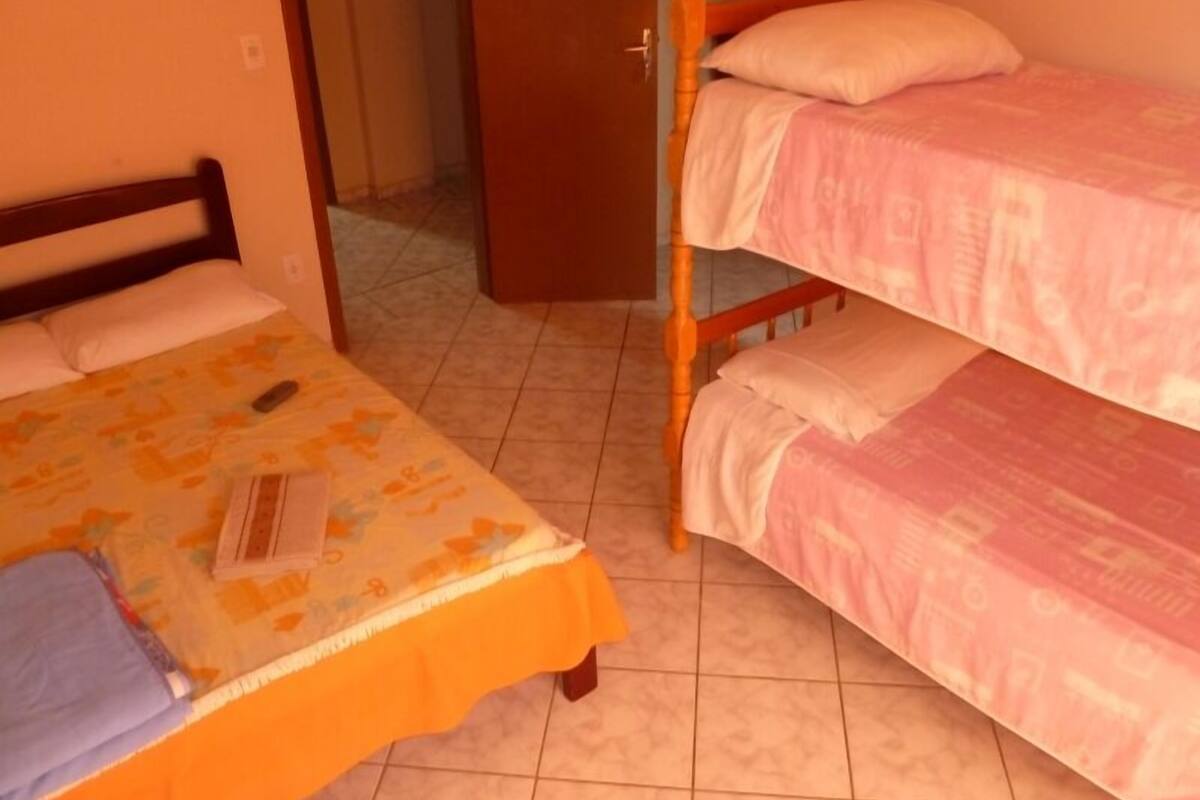 A room with two bunk beds, one with a yellow bedspread and the other with a pink bedspread.