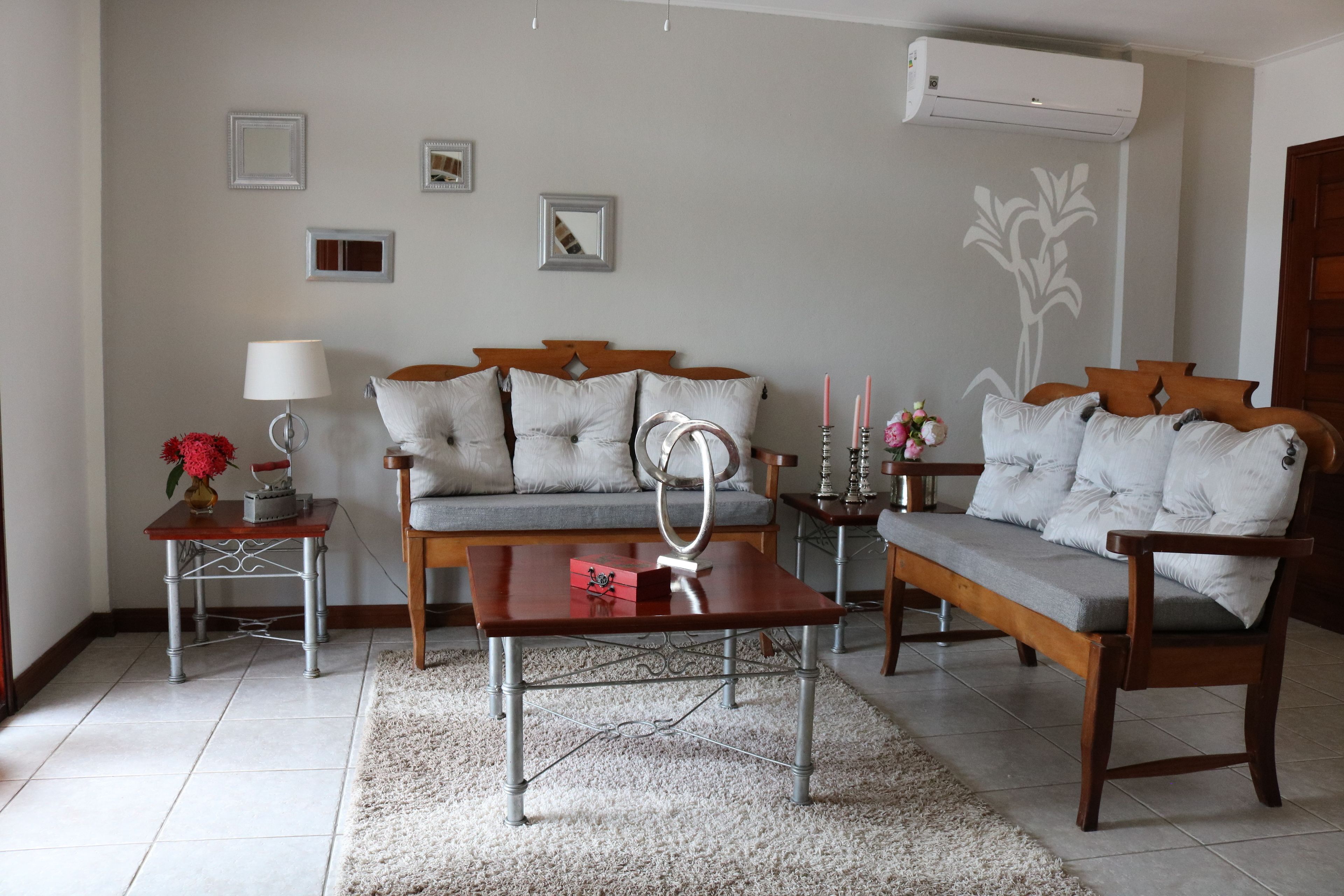 Een woonkamer met een bank, een salontafel, een bijzettafeltje met een lamp en een decoratieve spiegel.