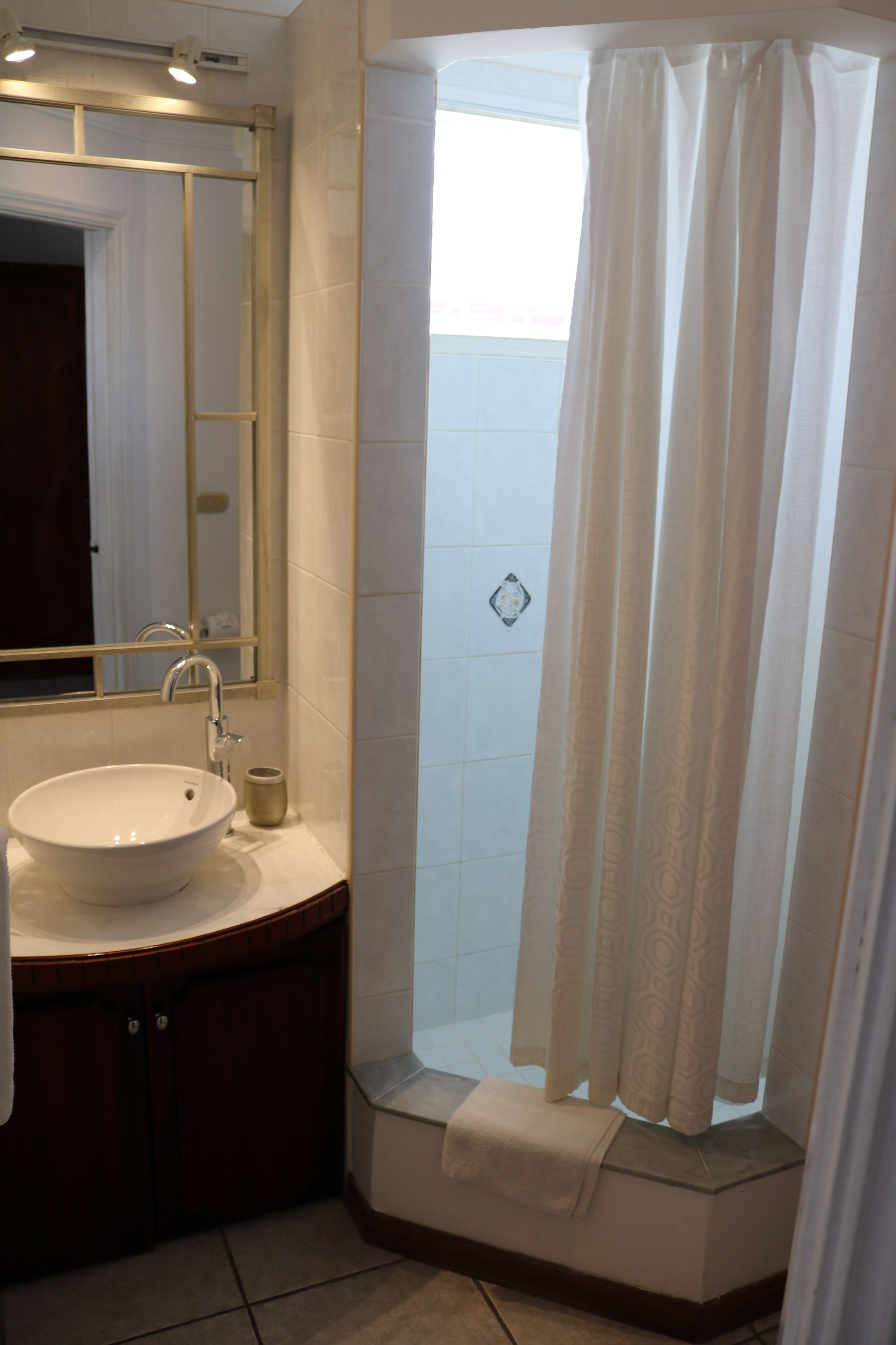 A bathroom with a white sink, mirror, and shower curtain.