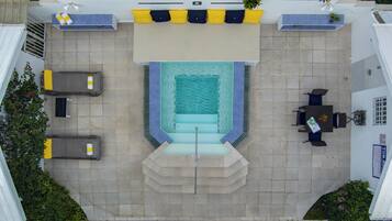 Vista aérea de una zona de piscina con una tumbona, una pequeña mesa con sillas y un banco.