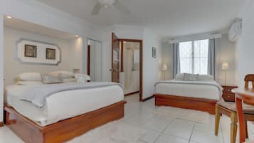 A bedroom with two beds, a ceiling fan, a wooden floor, and a white rug.