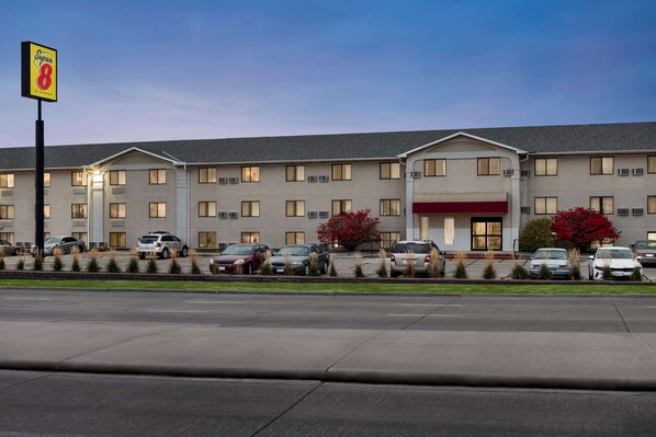 A Super 8 hotel with a parking lot and several cars parked in front.