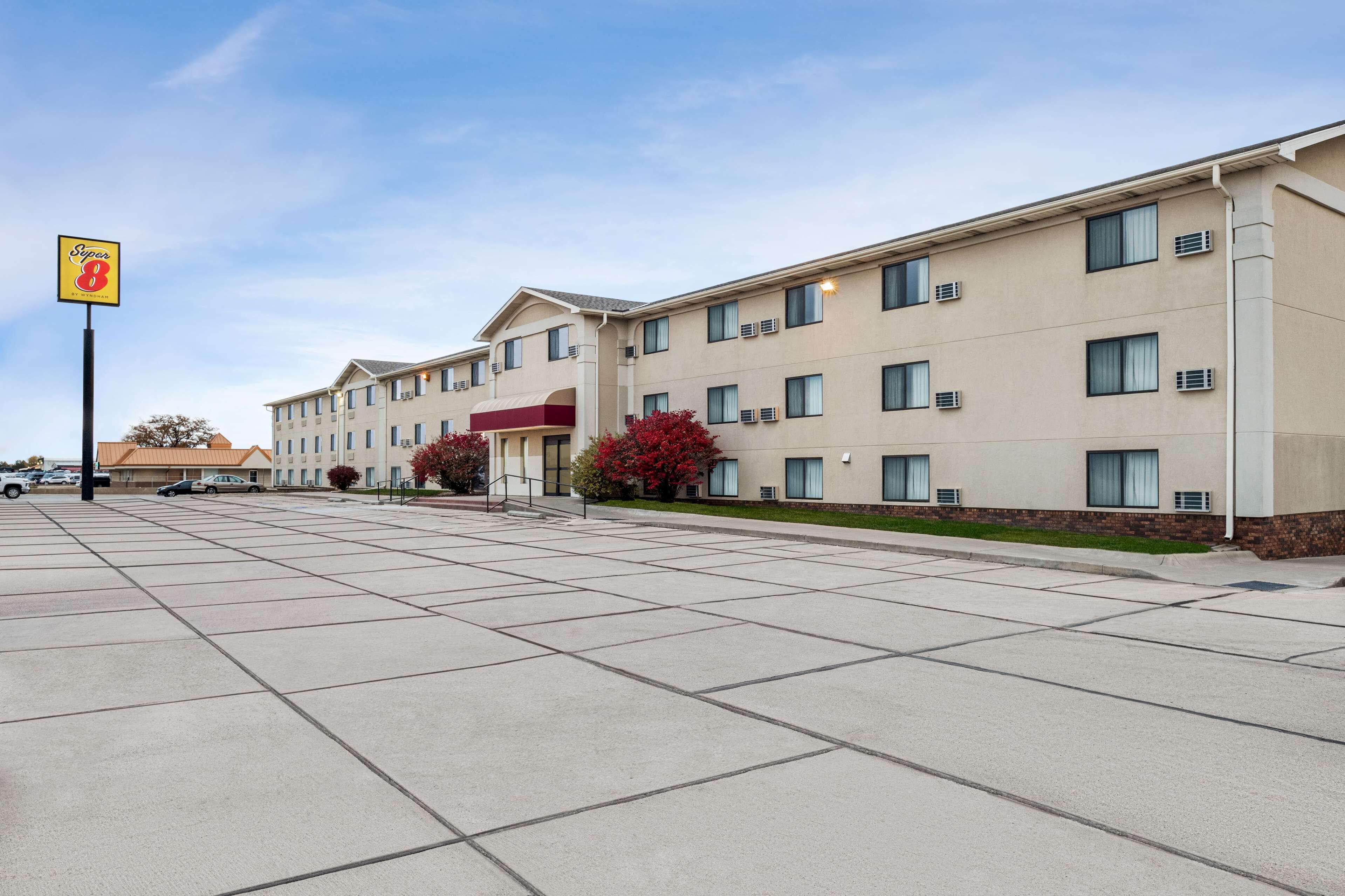 A multi-story hotel with a beige exterior, a parking lot, and a sign for 'Super 8' accommodations.