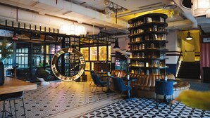 A modern interior with a circular bookshelf, leather seating, and patterned flooring. - Only YOU Hotel Atocha (Madrid)