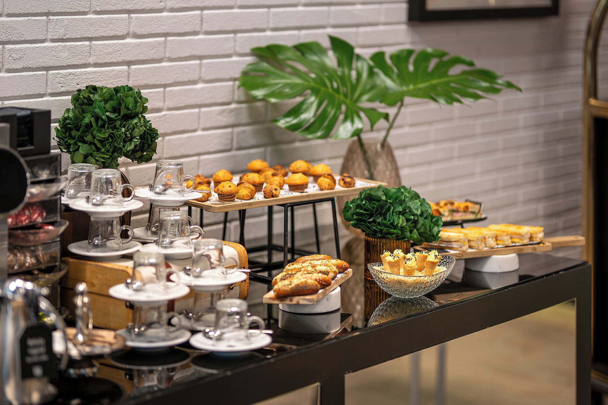 A buffet table with various food items and glassware.