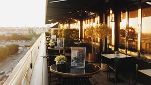 An outdoor seating area with tables and chairs, a menu board, and potted plants. - Only YOU Hotel Atocha (Madrid)