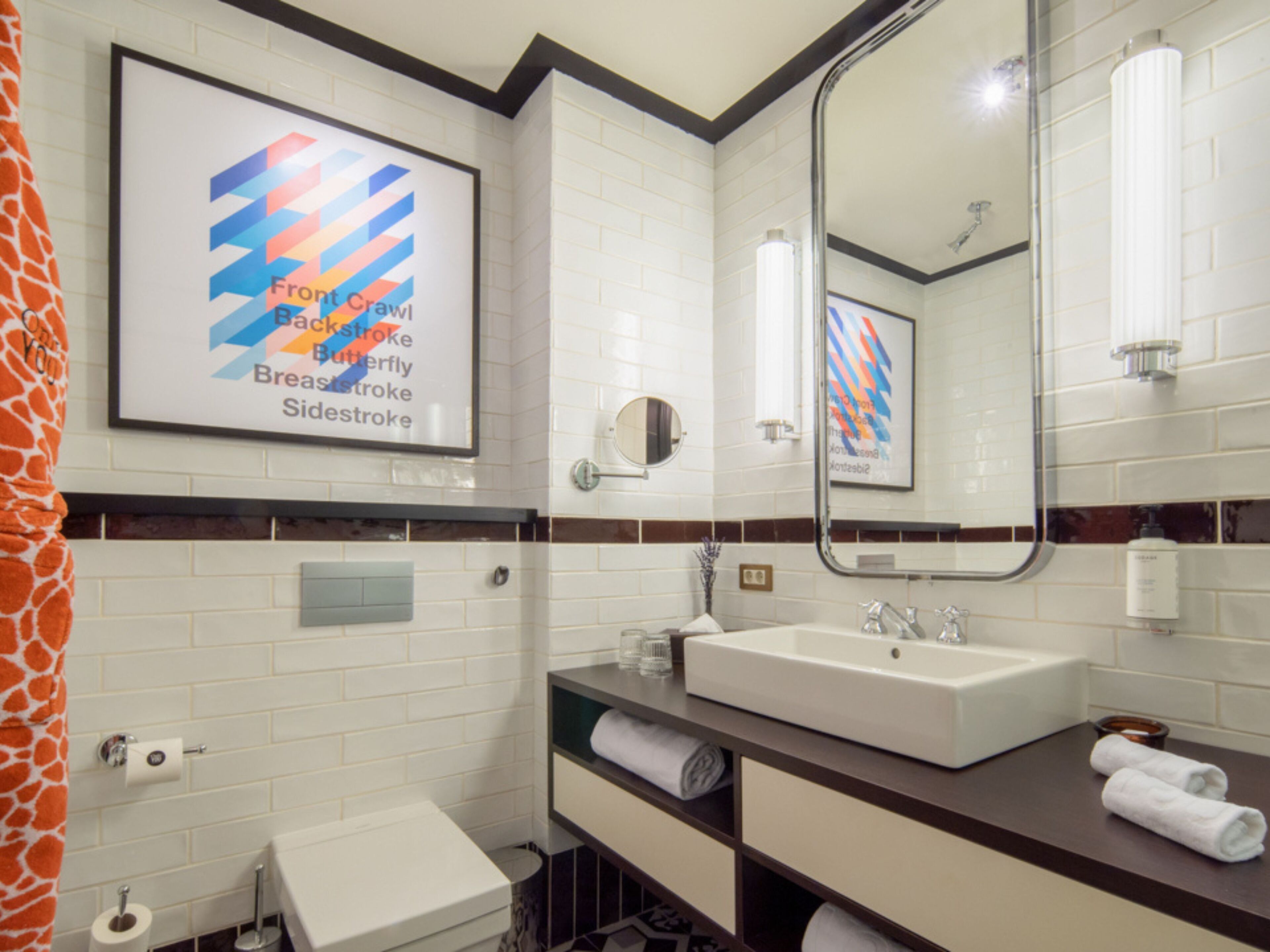 A modern bathroom with a white sink, a mirror, and a framed artwork depicting a colorful abstract design.