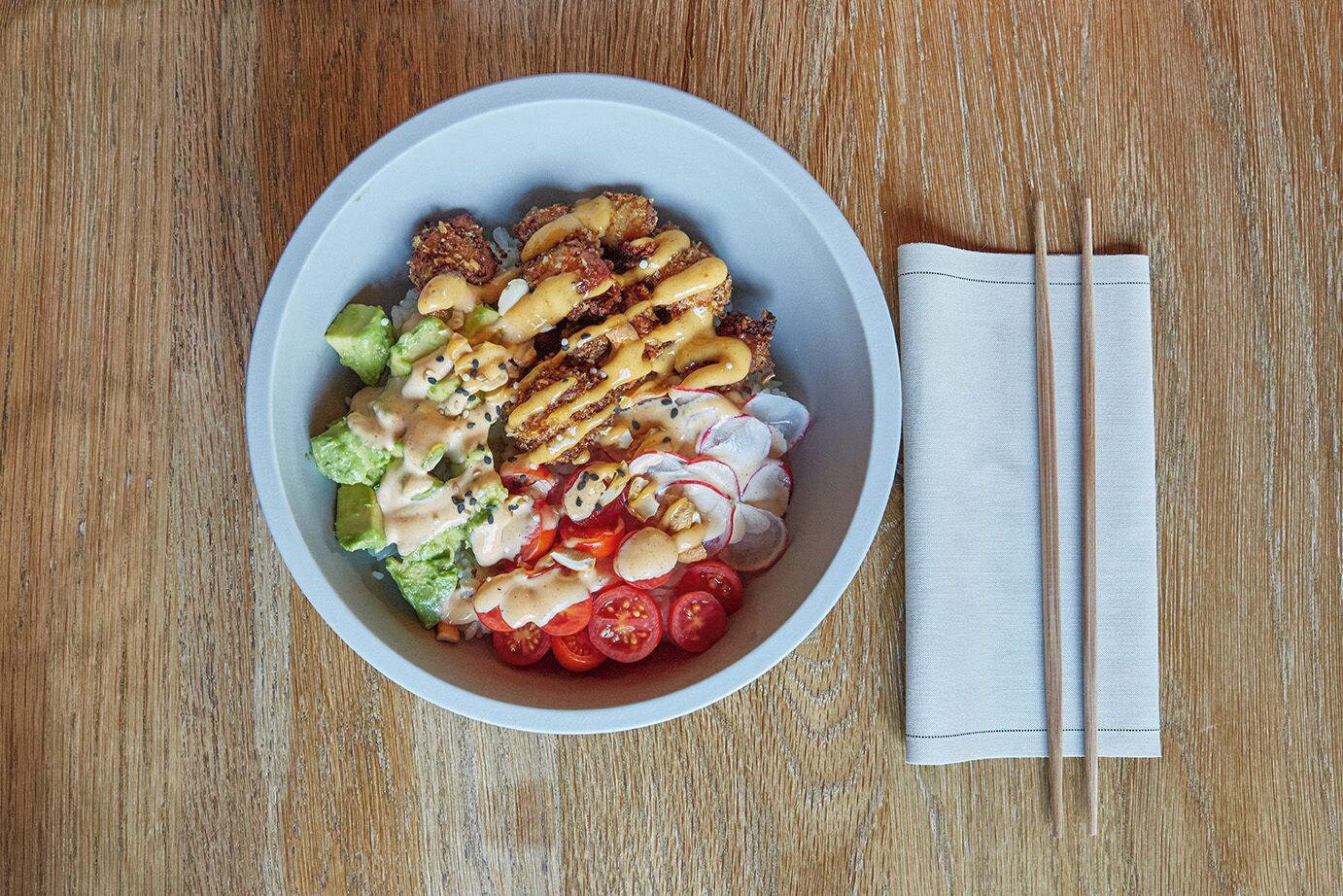 A bowl of salad with various ingredients on a wooden table.