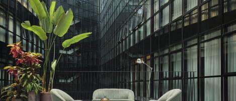 A modern interior with a glass facade, a seating area with a coffee table, and potted plants.