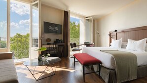 Et hotelværelse med seng, skrivebord, stol, fjernsyn og en balkon med udsigt.