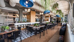 En moderne restaurant med flere spiseområder, hængende planter og industrielt lys.