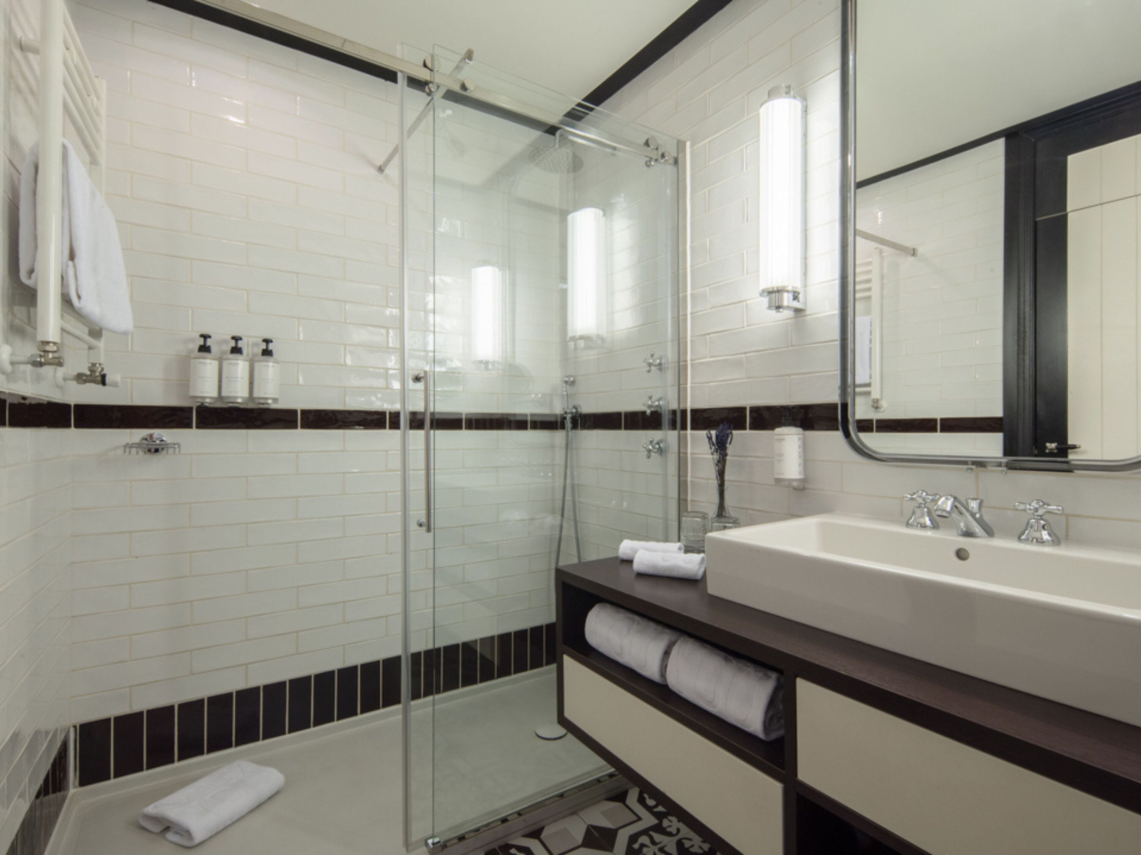Une salle de bain moderne avec une douche à parois de verre, un grand lavabo et un miroir.