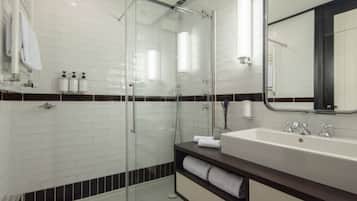 Une salle de bain moderne avec une douche à parois de verre, un grand lavabo et un miroir.