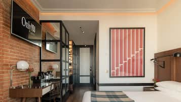 A hotel room with a bed, a desk, a chair, a mirror, and a large wall art piece.