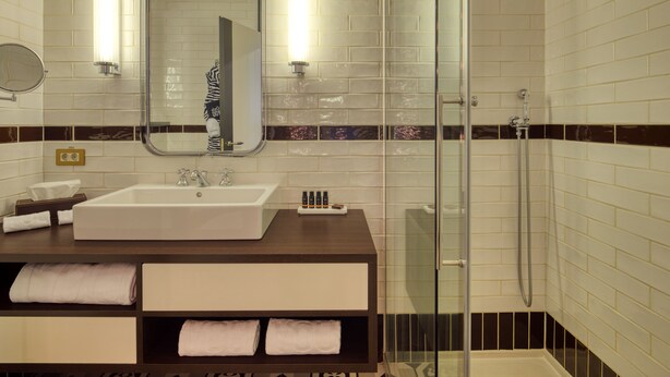 Baño con un espejo grande, un lavabo y cabina de ducha.