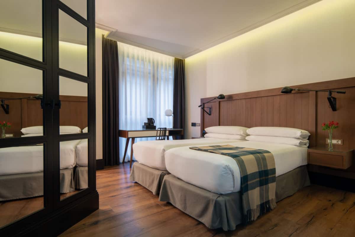 A hotel room with a large bed, a desk, and a chair.