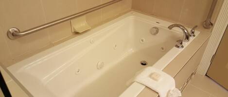 A bathtub with a grab bar, a towel, and a soap dish.
