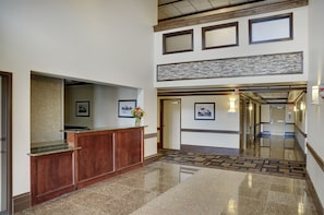 A hotel lobby with a reception desk, framed pictures on the walls, and a patterned carpet.