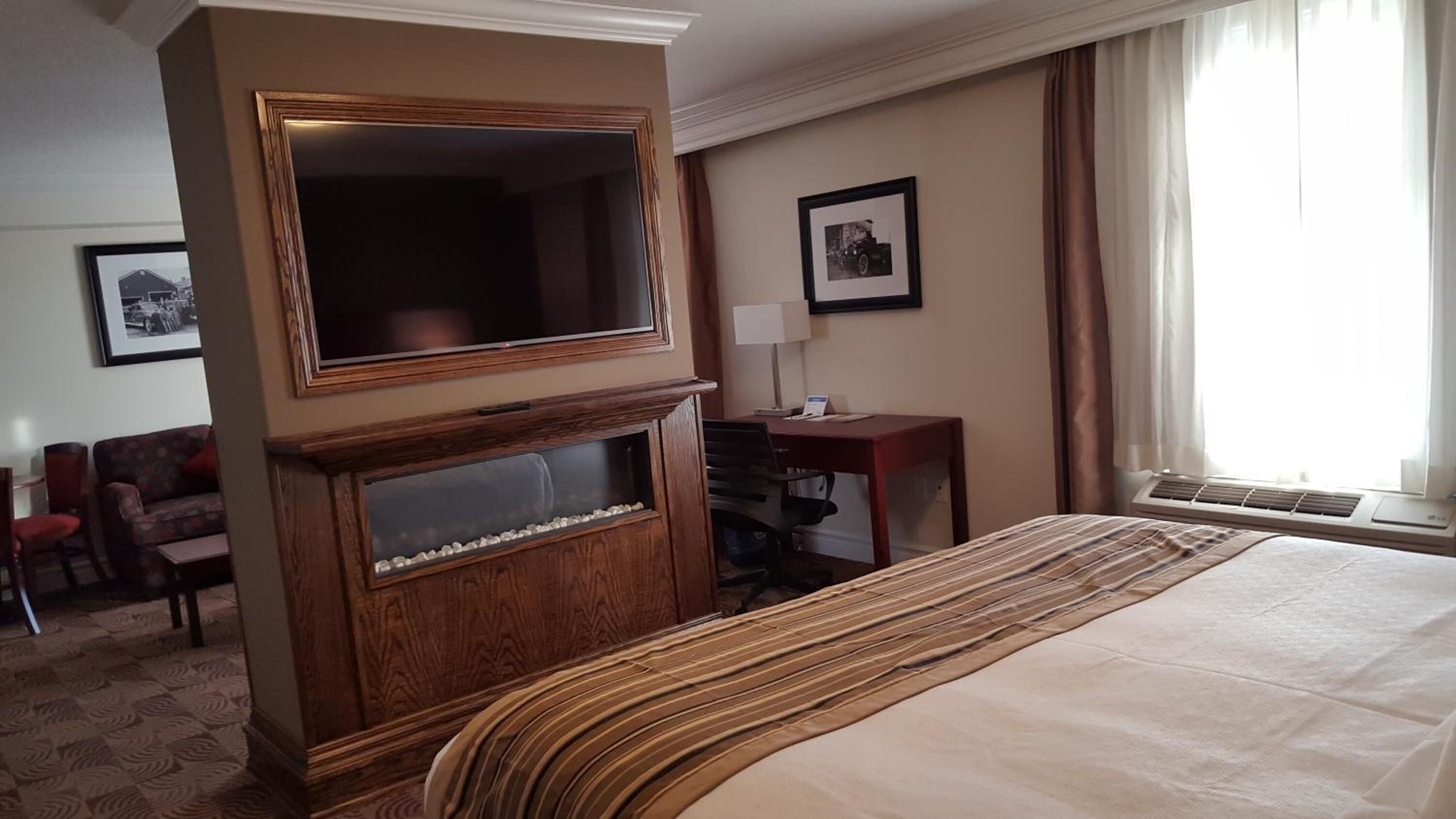 A hotel room with a large bed, a television, a desk, and a chair.