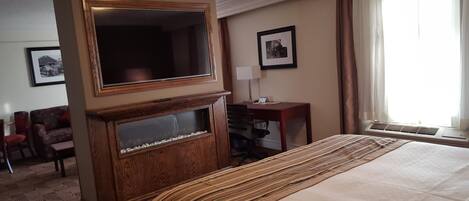 A hotel room with a large bed, a television, a desk, and a chair.