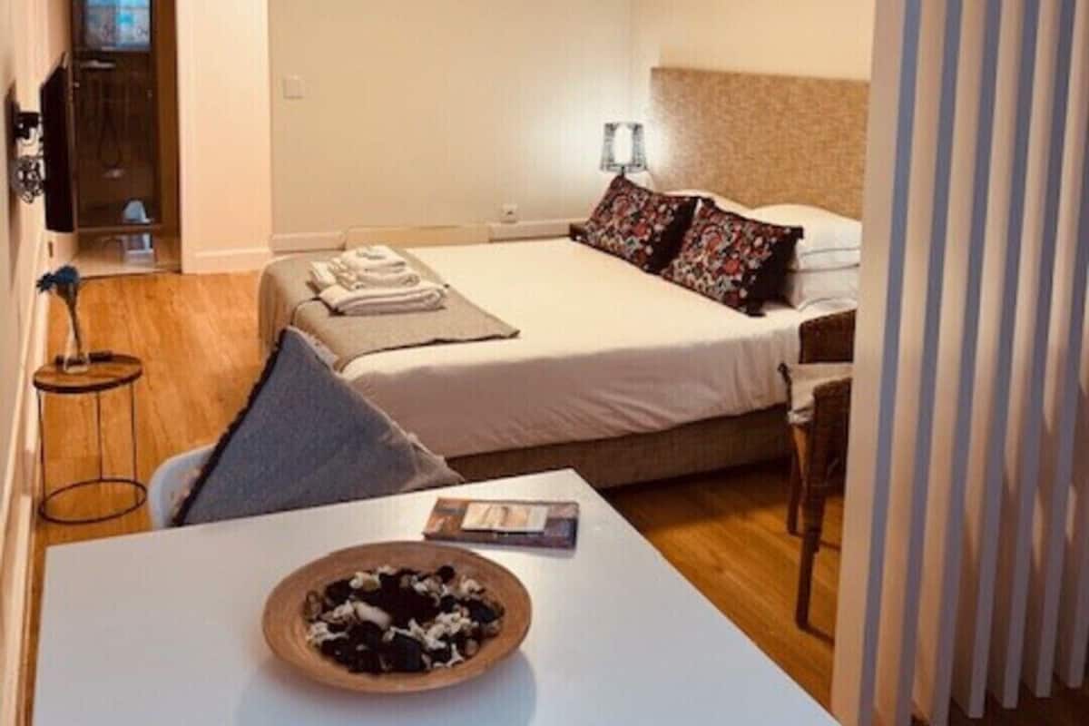 A small, neatly arranged bedroom with a bed, bedside table, and a chair.