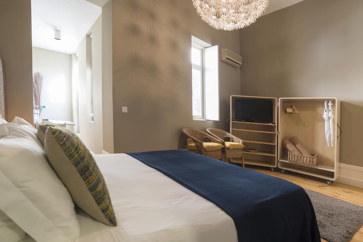 A bedroom with a bed, a TV, a wardrobe, and a chair.