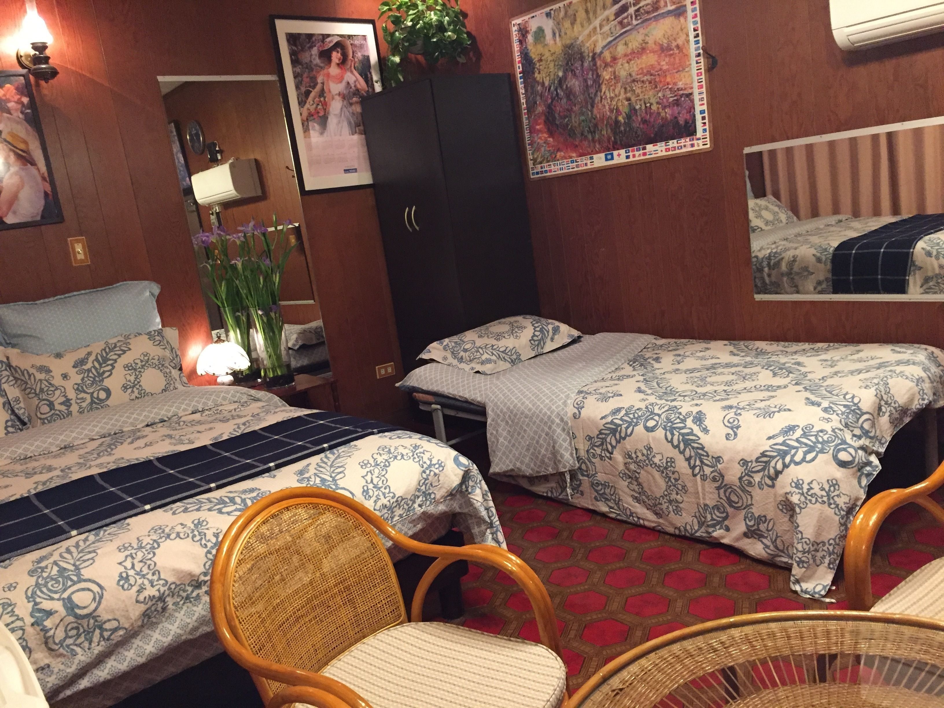 Una habitación de hotel con dos camas, un armario, una silla y un espejo.