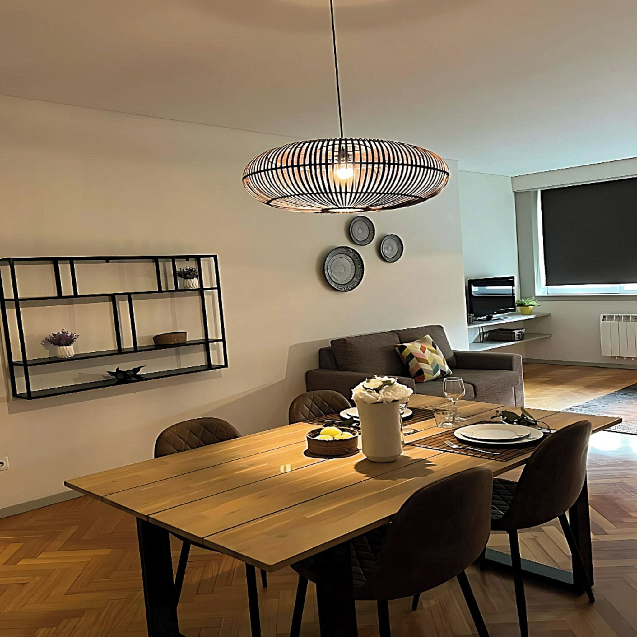 A dining area with a wooden table, chairs, and a hanging light fixture.