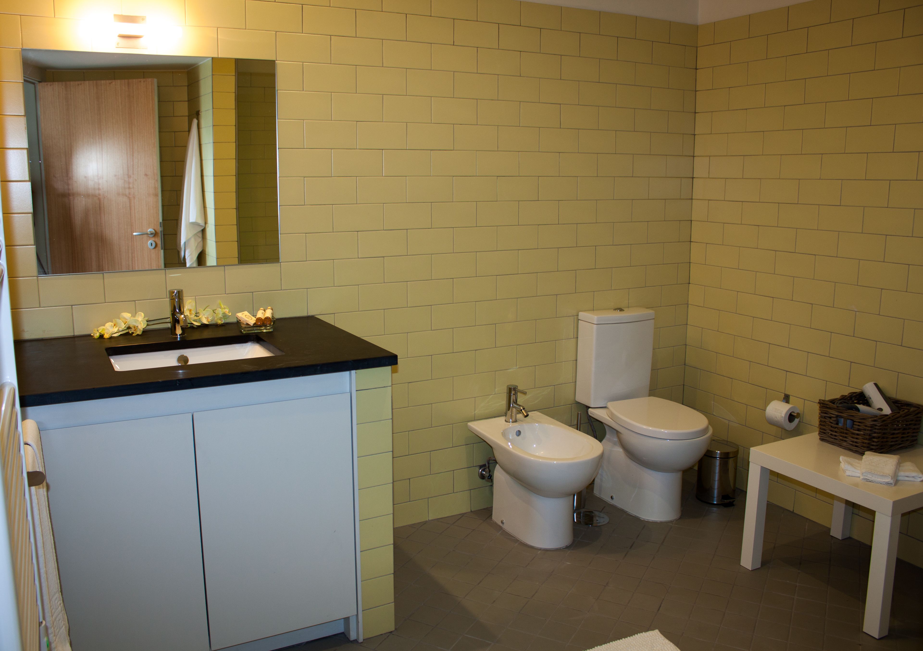 A bathroom with a sink, bidet, toilet, and a mirror.