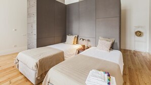 Een moderne hotelkamer met twee bedden, een grote garderobe en een houten vloer.