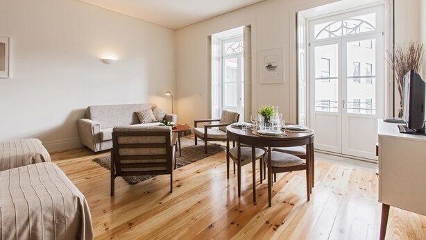 Een moderne woonkamer met een bank, fauteuils, een eettafel en een televisie.