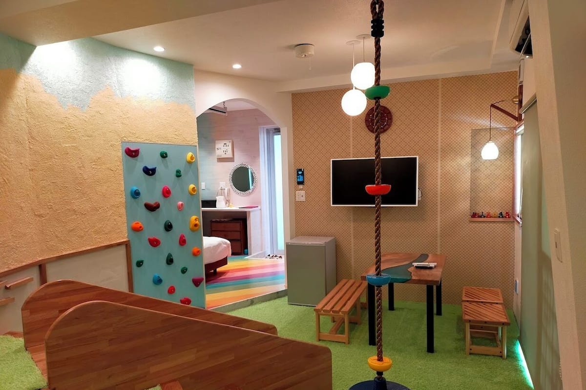 A children's playroom with a climbing wall, a play table, and a TV.