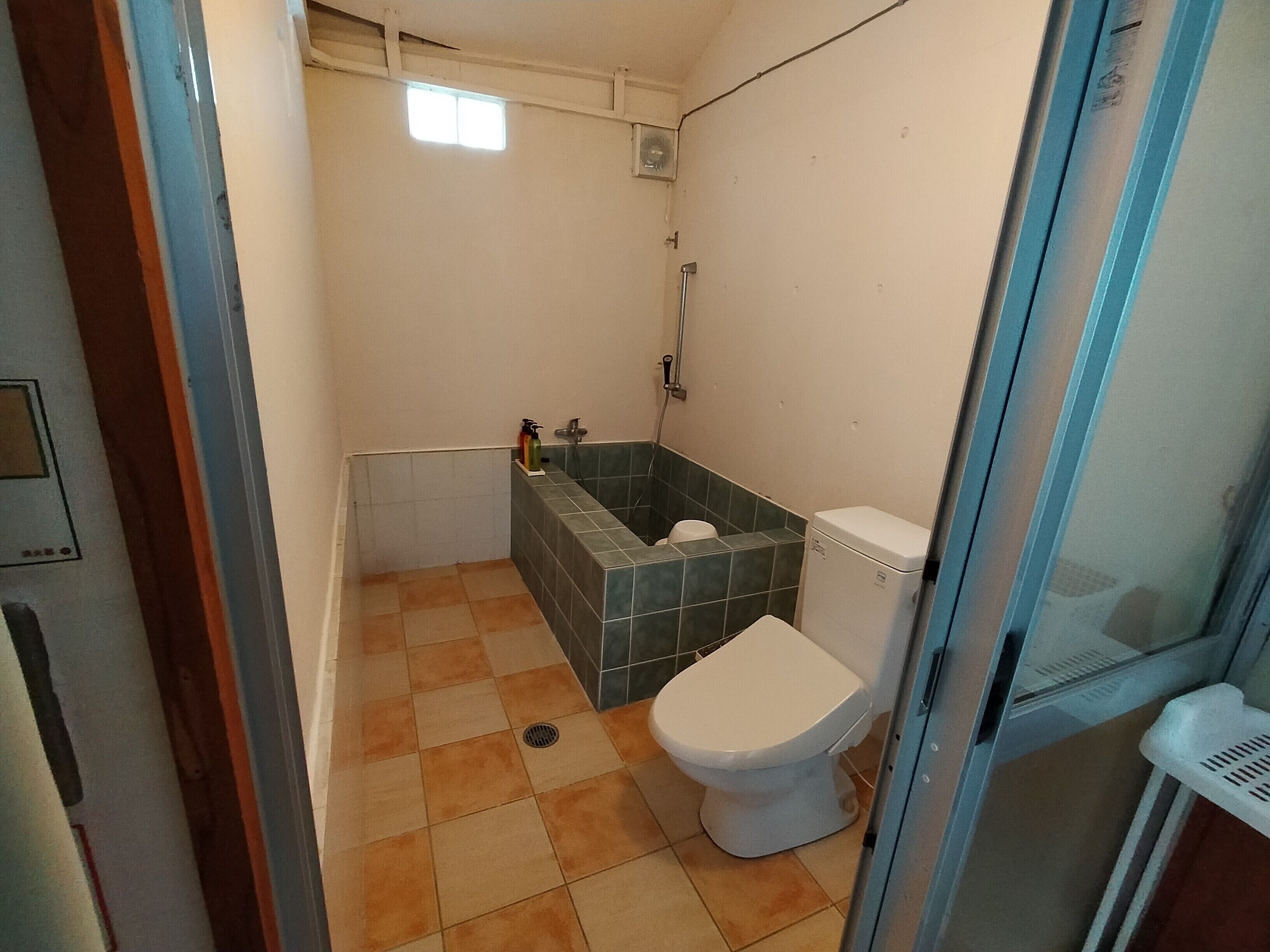 Une petite salle de bain avec des toilettes, une douche et un lavabo.